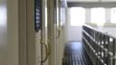 A row of cell doors and a walkway inside a prison. 